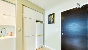 A kitchen with a white refrigerator, a sink with a faucet, and a cabinet. There is a door with a dark finish and a framed picture on the wall. - StayToronto - Terrace 21 Apartments (Toronto)