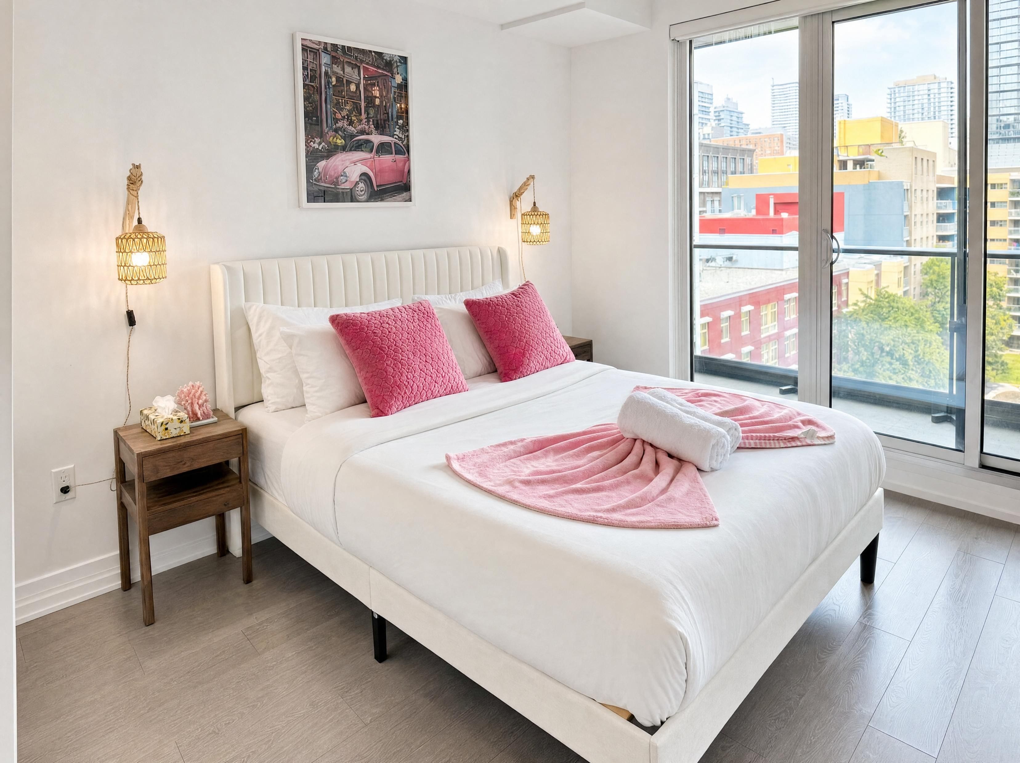 Une chambre d’hôtel avec un grand lit, une vue sur la ville et un tableau accroché au mur.