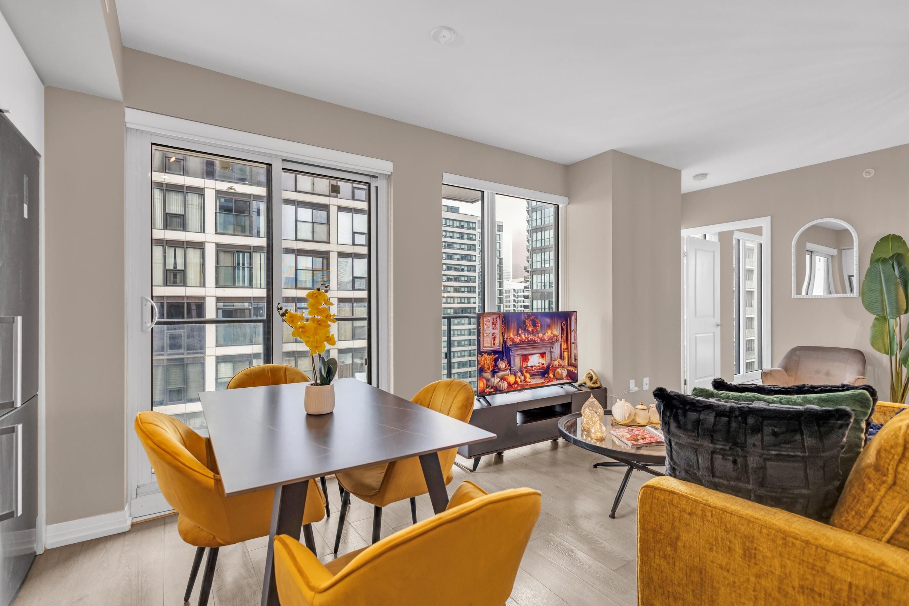 A modern living room with a dining area, large windows, and a fireplace.