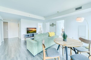 Una sala de estar moderna con un sofá verde, una mesa de comedor redonda de madera y un televisor de pantalla plana.