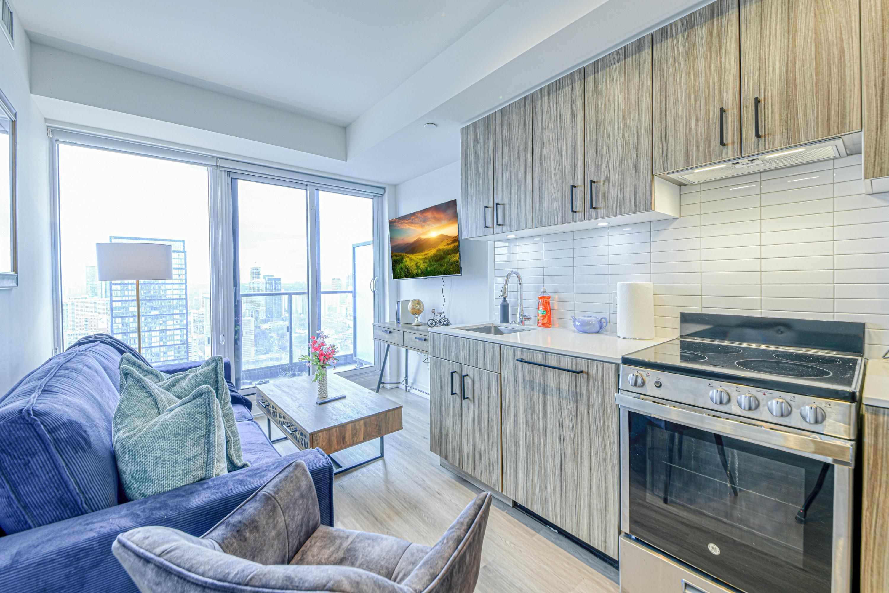 A modern kitchen with wooden cabinets, a built-in oven, and a large window offering a city view.