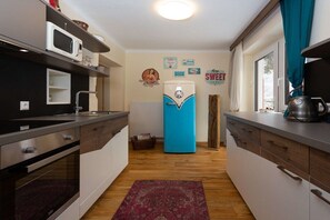 Eine kleine Küche mit modernen Geräten, einem Retro-Kühlschrank und Holzboden.