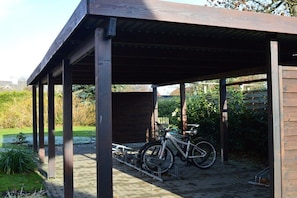 Ein überdachter Außenbereich mit Fahrradständer und Holzkonstruktion.