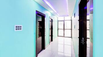 Un pasillo con paredes color turquesa, suelo de baldosas y puertas que dan a habitaciones.