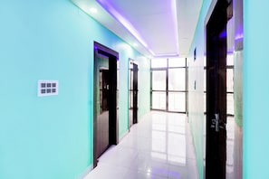 A hallway with teal walls, a tiled floor, and doors leading to rooms.