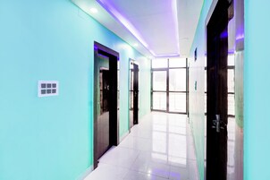 A hallway with teal walls, a tiled floor, and doors leading to rooms.