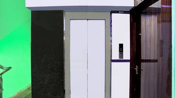 A door with a digital display, a green wall, and a marble floor.