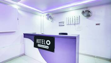 Una mesa de recepción de hotel con un cartel que dice 'HOTEL', una etiqueta de servicio de empresa y un equipo de aire acondicionado instalado en la pared.