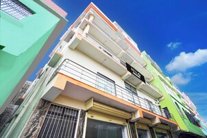 A multi-story hotel with balconies, a visible sign indicating it is a hotel, and a clear blue sky in the background.