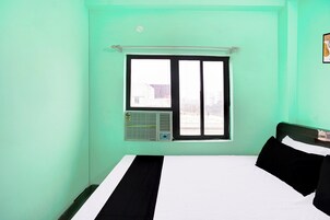 A room with a bed, a window, and an air conditioning unit.