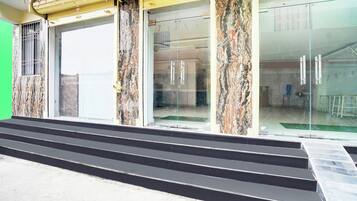 Una entrada de edificio con columnas de mármol, un vidrio y una serie de escalones negros que conducen a ella.