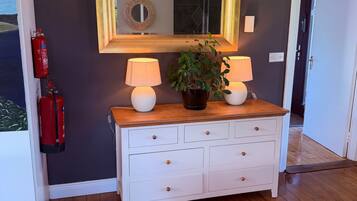 A white dresser with two lamps, a mirror, and a potted plant.