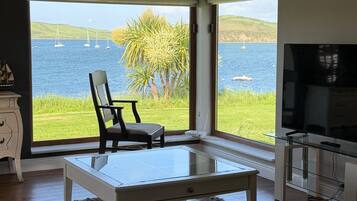 A modern living room with a large window overlooking a body of water and sailboats.