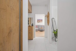Ein Flur, der in einen Wohnbereich mit einer Couch, einem Couchtisch und einem Stadtbild führt.
