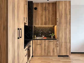 Eine moderne Küche mit Holzschränken, einer schwarzen Marmor-Spritzschutzleiste und einem Edelstahl-Spülbecken.