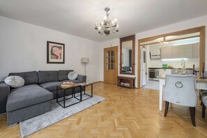 Un salon moderne avec un canapé gris, une table basse et un lustre.