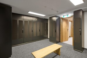 A locker room with multiple lockers, a bench, and a door leading to another room. - Modern suite with outdoor sauna (Gaschurn)