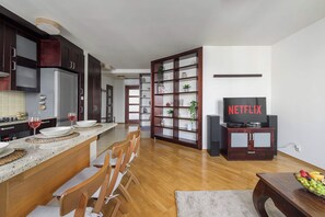 A modern kitchen with a built-in refrigerator, a dining area with wooden chairs, and a living room with a Netflix TV. - Lumina 3-room Apart & Parking & Balcony I AC (Warszawa)