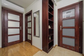A hallway with wooden doors, a mirror, and a built-in shelving unit. - Lumina 3-room Apart & Parking & Balcony I AC (Warszawa)