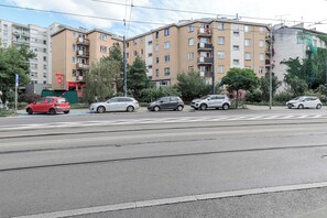 Eine Straße mit mehrstöckigen Wohnhäusern, einer Straßenbahnlinie und geparkten Autos.