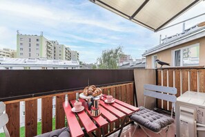 Eine Dachterrasse mit einem für zwei Personen gedeckten Tisch, einer Bank und Blick auf die umliegenden Gebäude.