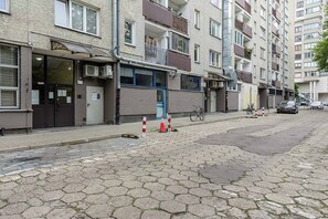 A residential street with apartment buildings, a bicycle, and a car parked on the side. - Lumina 3-room Apart w/ Balcony near Arkadia Mall (Warszawa)