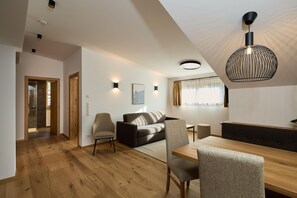 A modern living room with a sofa, chairs, a dining table, and a unique pendant light. - Modern suite with outdoor sauna (Gaschurn)