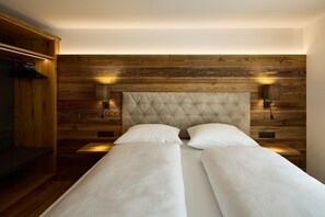 A double bed with a tufted headboard, two bedside tables, and wall-mounted lamps. - Penthouse suite with outdoor sauna (Gaschurn)