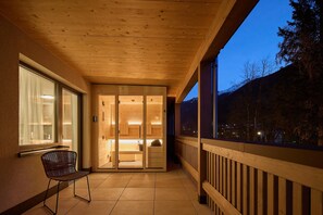 A wooden balcony with a view of a mountain at dusk. - Penthouse suite with outdoor sauna (Gaschurn)