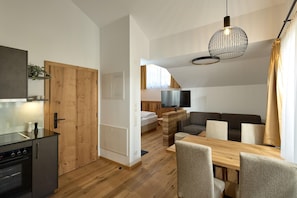 A modern kitchen with a built-in oven and a dining area with a wooden table and chairs. - Penthouse suite with panoramic views (Gaschurn)