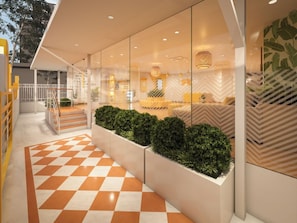 Um lobby de hotel moderno com piso xadrez, uma escadaria e uma área de estar com parede estampada.