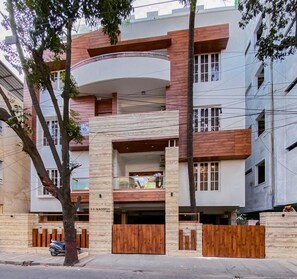 Un immeuble résidentiel moderne à plusieurs étages, doté d’un balcon incurvé, d’un garage et d’une clôture en bois.
