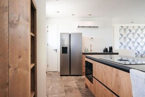 A modern kitchen with a built-in refrigerator, a coffee maker, and a patterned backsplash. - Oceanfront 2BR Condo • One Mambo 5 by Bocobay (Willemstad)