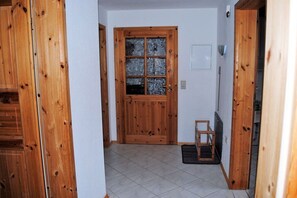 A hallway with a wooden door, a small wooden stool, and a tiled floor. - Holiday apartment with 2 bedrooms (Norden)