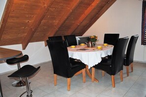 A dining area with a round table, black chairs, and a white tablecloth. - Holiday apartment with 2 bedrooms (Norden)