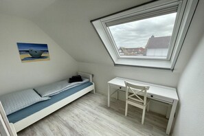 Ein Schlafsaalzimmer mit Etagenbett, Schreibtisch und Fenster mit Blick auf eine Stadtlandschaft.