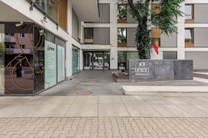 Une entrée moderne, avec une façade en verre, un arbre et un drapeau.