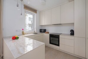 Cozinha moderna com ilha central, forno embutido e micro-ondas.