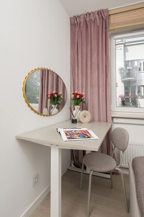 A room with a white desk, a chair, a mirror, and a window with pink curtains. - Lumina Spacious 4 Room Apartment with Parking (Warszawa)
