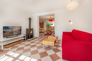 A living room with a fireplace, a television, and a red sofa. - The Beautiful House in Sellin—Pure Relaxation with a Sauna and Fireplace (Sellin)
