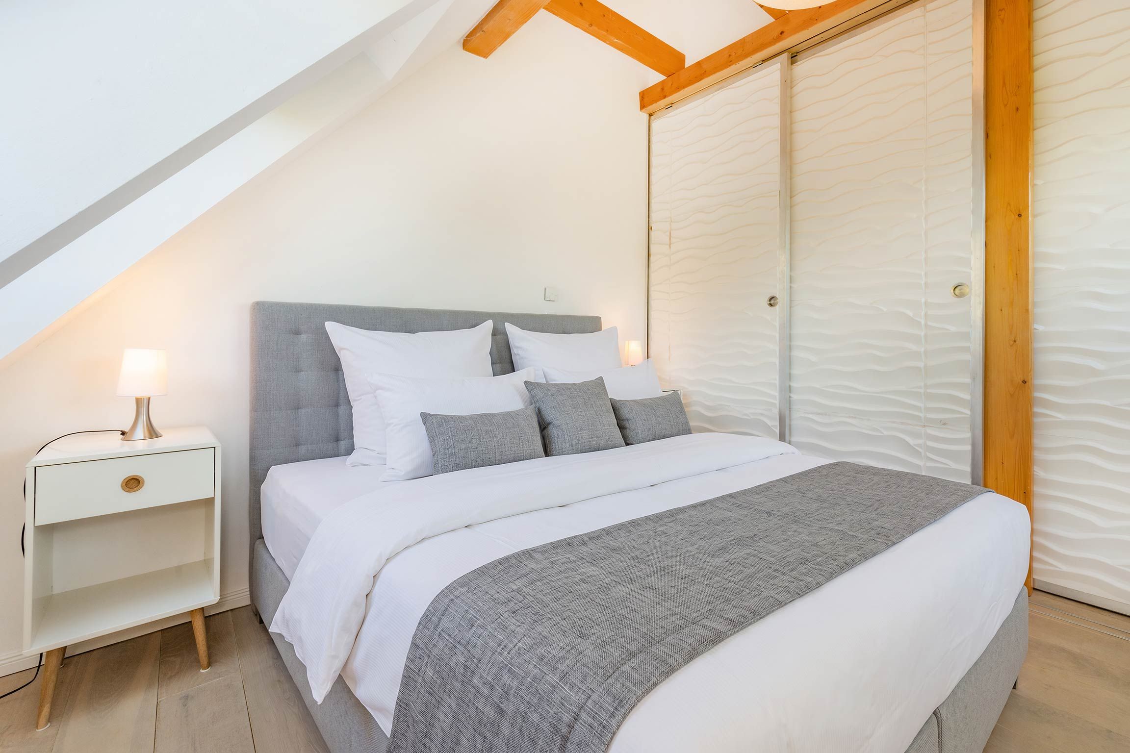 A bedroom with a bed, nightstand, and a closet.