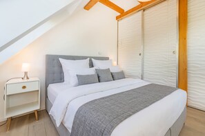 A bedroom with a bed, nightstand, and a closet. - The Beautiful House in Sellin—Pure Relaxation with a Sauna and Fireplace (Sellin)