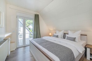 Een slaapkamer met een groot bed, een nachtkastje, een raam met gordijnen en uitzicht op buiten.