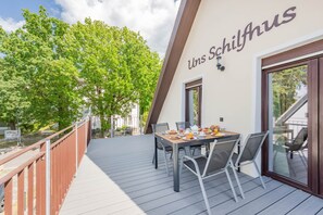 Ein Balkon mit einem Frühstückstisch, mit Blick auf eine von Bäumen gesäumte Straße.