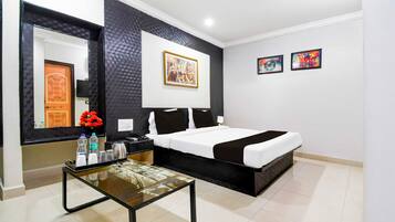 Quarto de hotel com cama, mesa de cabeceira com abajur, espelho e obras de arte na parede.