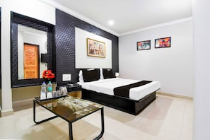 A hotel room with a bed, a bedside table with a lamp, a mirror, and artwork on the wall. - Collection O Railway Station (Raipur)