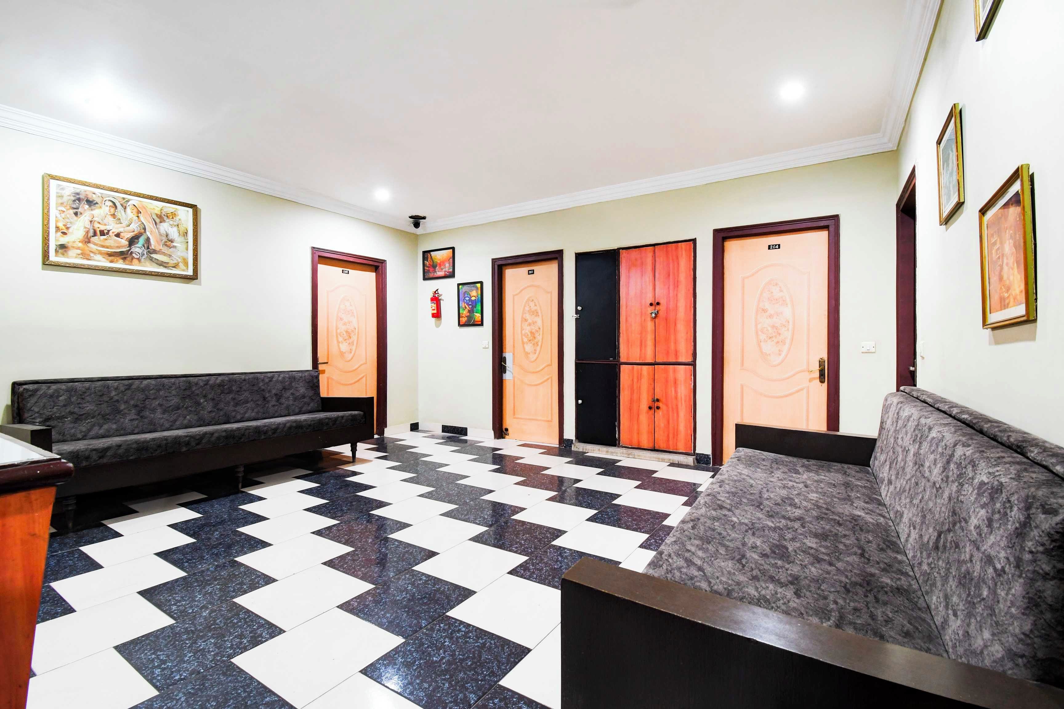 Um hall com piso quadriculado, dois sofás e um balcão de recepção.