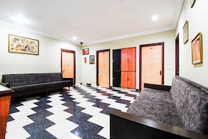 Um hall com piso quadriculado, dois sofás e um balcão de recepção.