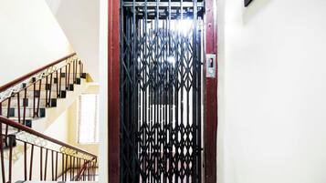 Escada com portão de metal no topo, dando acesso a um quarto.