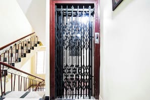 Escada com portão de metal no topo, dando acesso a um quarto.